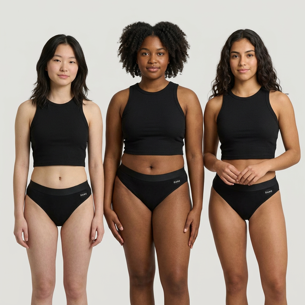 Three models wearing a matching black two-piece activewear set consisting of a cropped tank top and high-waisted briefs, shown against a solid light gray background.