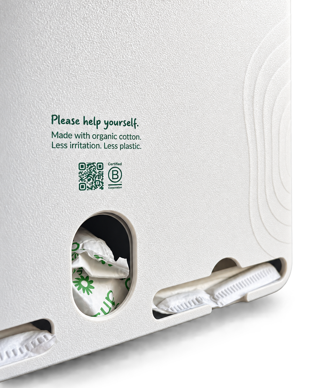Close-up of the back of a white textured disposable diaper bag or liner package, showing printed green text, a QR code, a Certified B Corp logo, and partial white diaper packs stored in cutout slots.